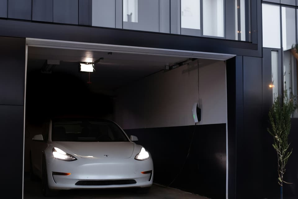 A white car parked inside a lit garage with the door open