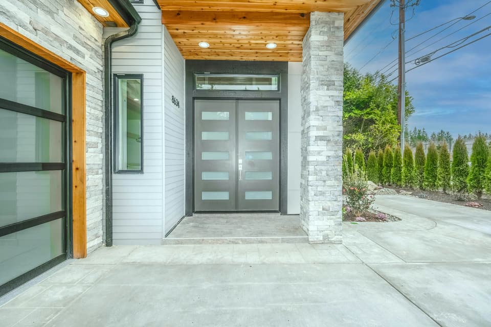 A modern house with a glass-panel garage door beside a double front door