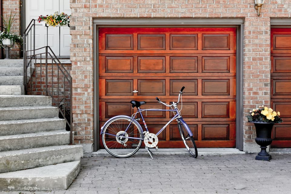 A wood raised-panel garage door with a bicycle parked in front