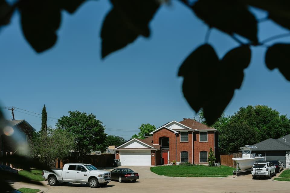 A brick two-story house with a white garage door on a suburban street